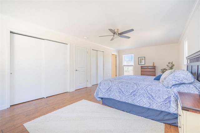 bedroom with ceiling fan, multiple closets, and wood finished floors