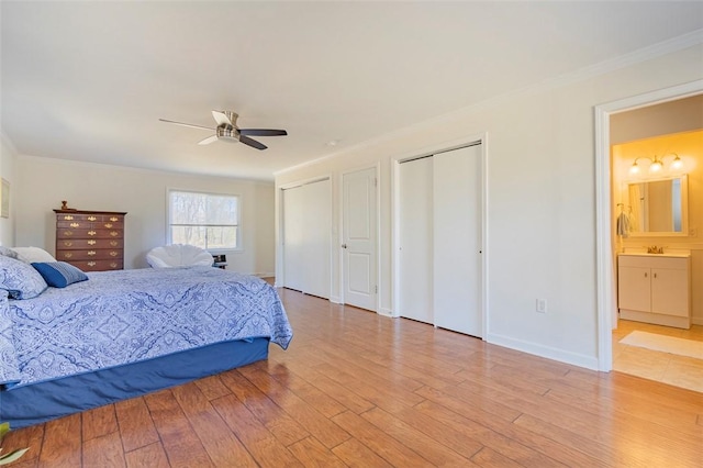 bedroom featuring ornamental molding, light wood-type flooring, a sink, and two closets