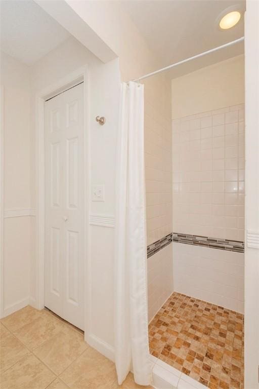 full bath with tiled shower and tile patterned flooring