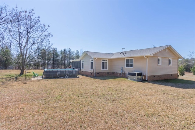 back of property featuring crawl space, a swimming pool, a lawn, and cooling unit