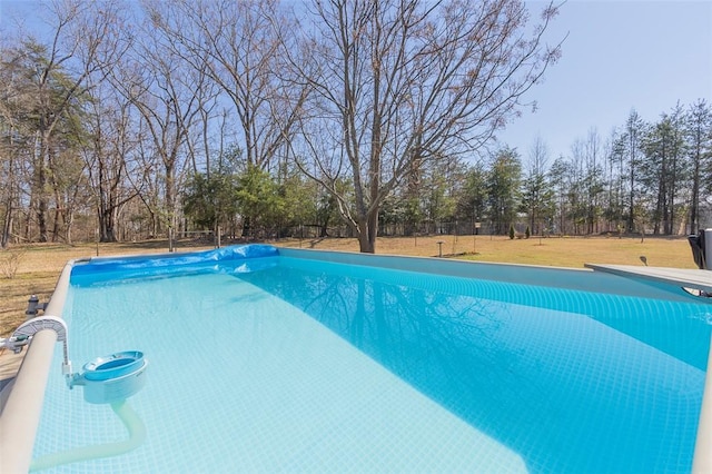 outdoor pool with a diving board, a yard, and fence