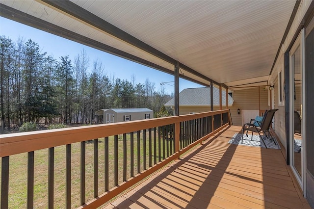 wooden deck featuring an outbuilding, a yard, and a storage shed