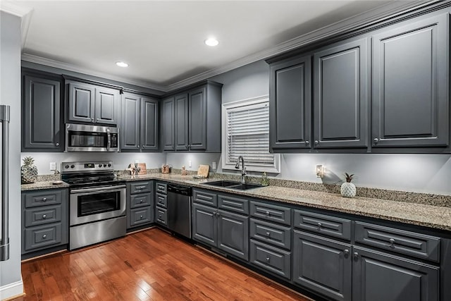 kitchen with light stone countertops, dark wood-style flooring, stainless steel appliances, and a sink