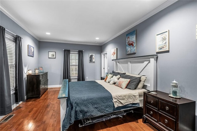 bedroom featuring wood-type flooring, visible vents, crown molding, and baseboards