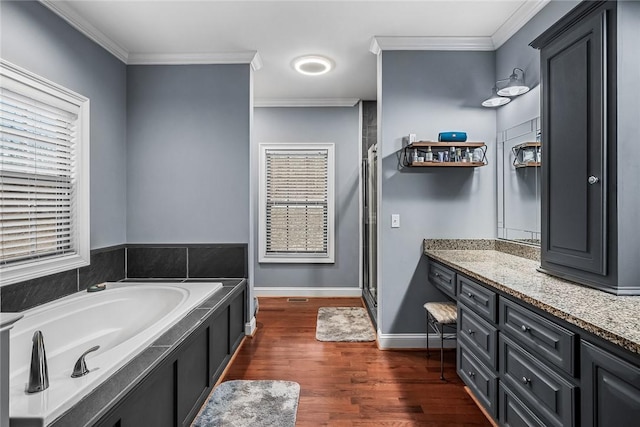 full bath with a garden tub, wood finished floors, vanity, a stall shower, and crown molding