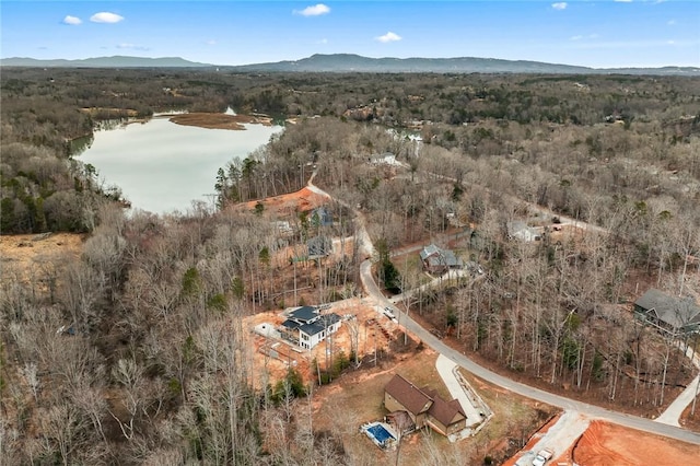 birds eye view of property featuring a water and mountain view and a wooded view