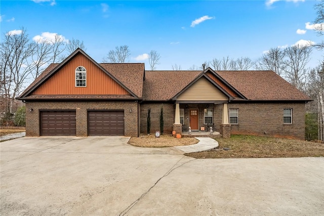 craftsman-style house featuring a garage, brick siding, driveway, and roof with shingles