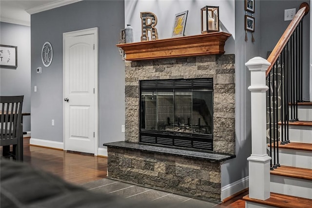 interior space featuring baseboards, ornamental molding, wood finished floors, and a stone fireplace