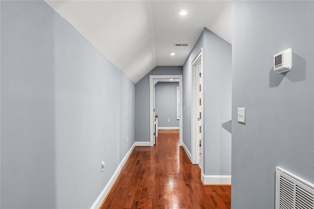 corridor with baseboards, visible vents, vaulted ceiling, and hardwood / wood-style floors