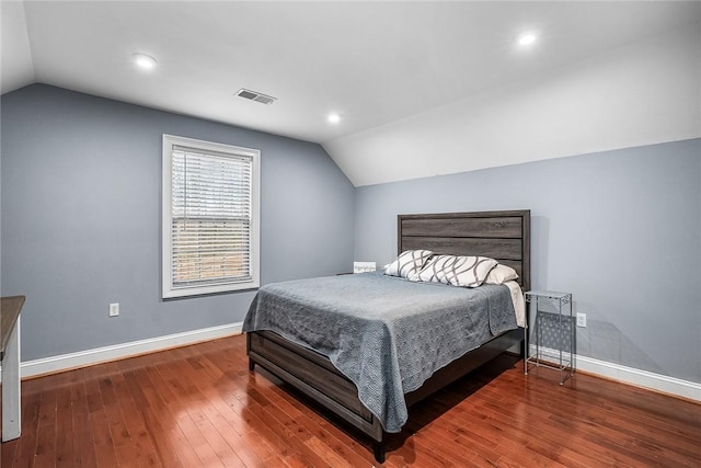 bedroom with lofted ceiling, hardwood / wood-style floors, visible vents, and baseboards