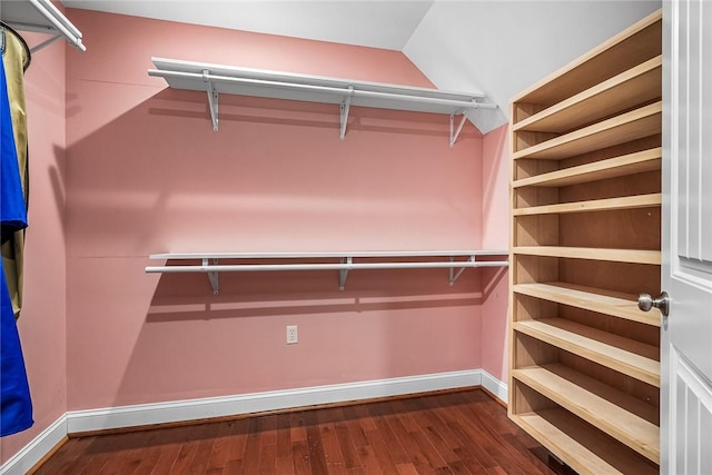 spacious closet with lofted ceiling and dark wood-type flooring