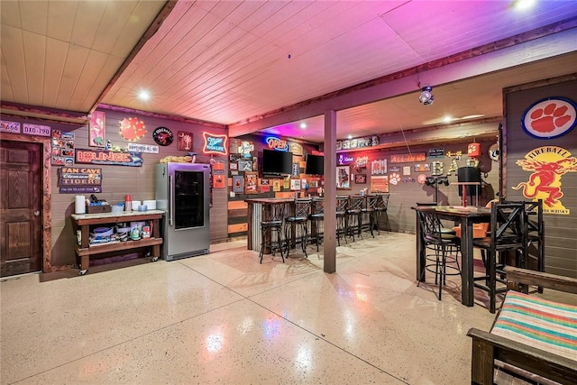 bar with a dry bar, smart refrigerator, and speckled floor