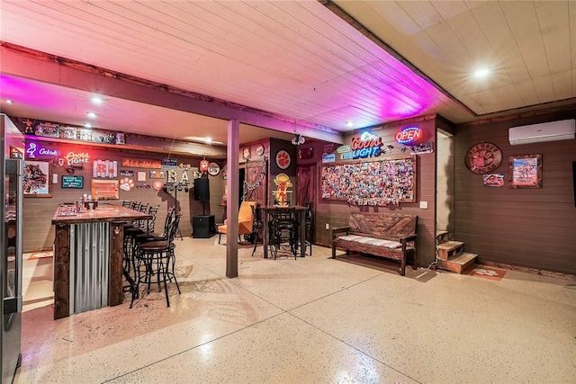 bar featuring speckled floor, a bar, wood walls, and a wall unit AC