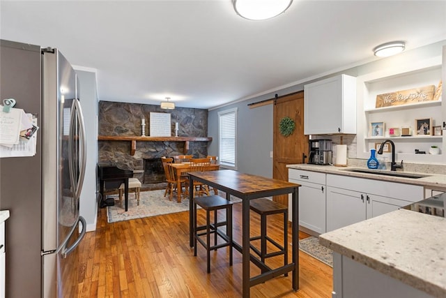 kitchen featuring a barn door, light wood-style flooring, a sink, and freestanding refrigerator