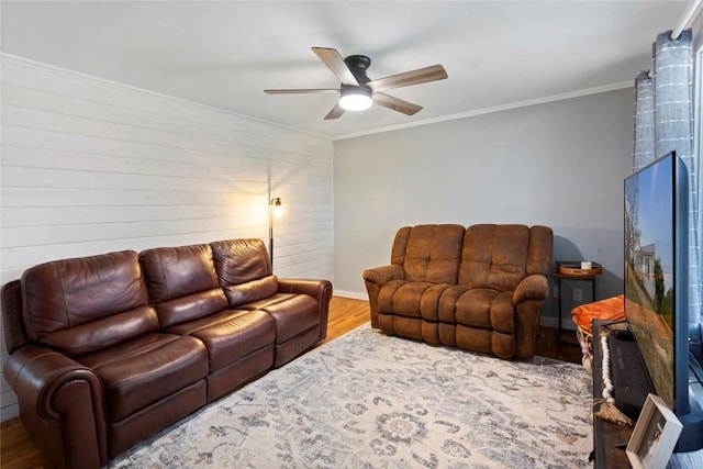 living room with a ceiling fan, baseboards, ornamental molding, and wood finished floors