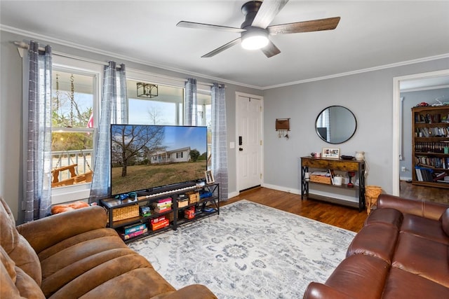 living room featuring ceiling fan, crown molding, baseboards, and wood finished floors