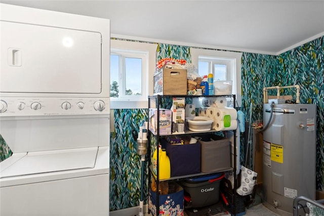 laundry area featuring laundry area, electric water heater, wallpapered walls, and stacked washer and clothes dryer