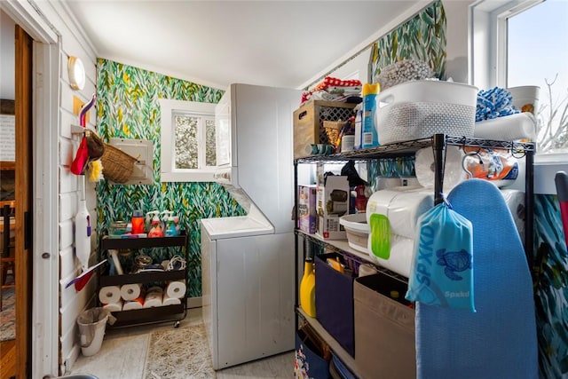 washroom featuring laundry area, stacked washing maching and dryer, wallpapered walls, and wood finished floors