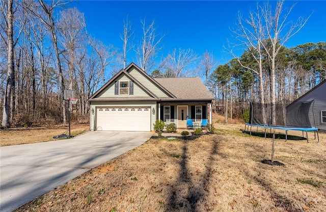 view of front of house featuring a trampoline, roof with shingles, a porch, a garage, and driveway