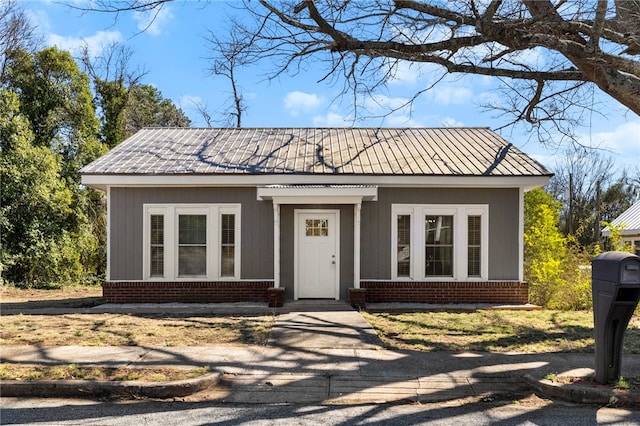 bungalow-style home with brick siding and metal roof