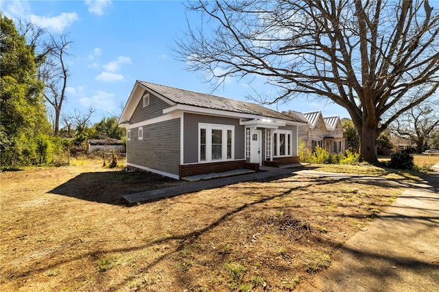 view of home's exterior with entry steps, brick siding, and metal roof