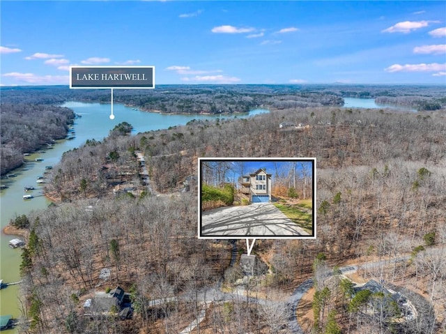 birds eye view of property with a wooded view and a water view