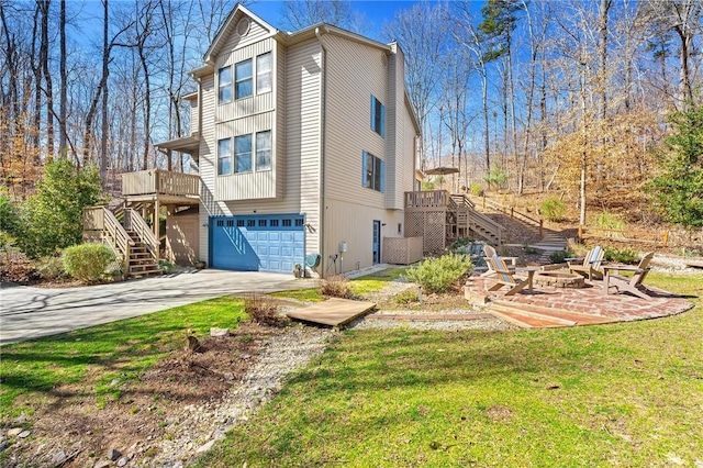 view of side of property with an outdoor fire pit, a garage, driveway, a wooden deck, and stairs