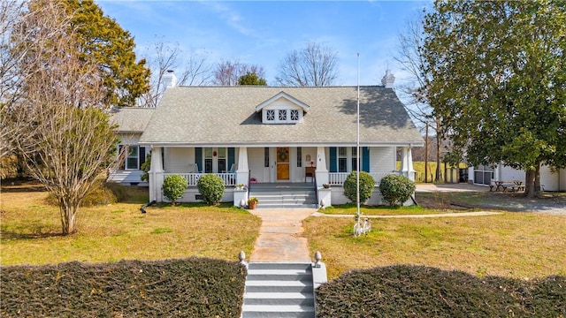 cape cod-style house featuring a chimney, a porch, and a front yard