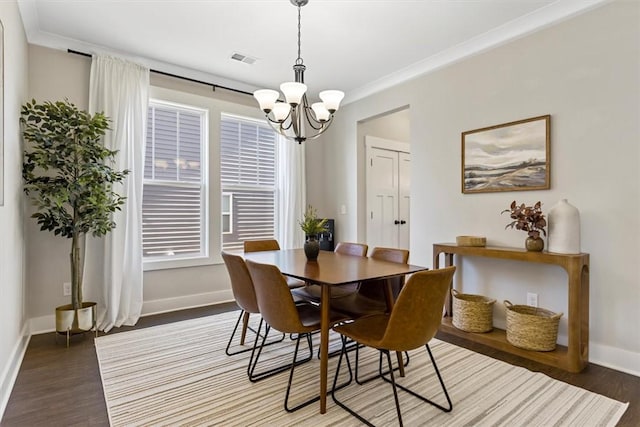 dining area featuring baseboards, visible vents, ornamental molding, wood finished floors, and an inviting chandelier