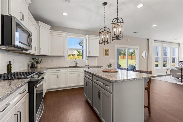 kitchen featuring a center island, dark wood-style flooring, stainless steel appliances, backsplash, and a kitchen breakfast bar