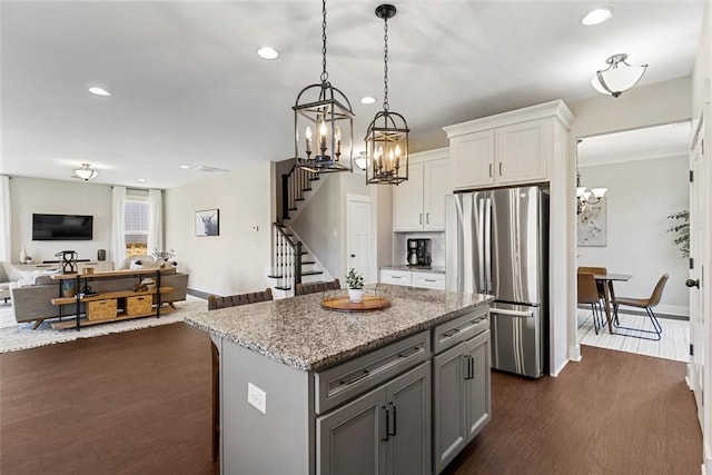 kitchen featuring white cabinets, open floor plan, dark wood-style flooring, freestanding refrigerator, and light stone countertops