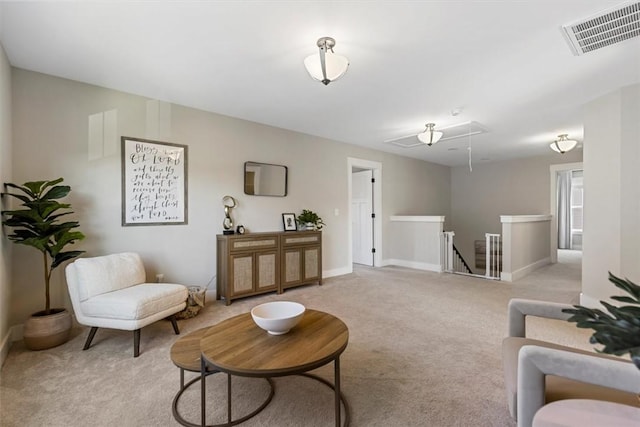 living area with light carpet, baseboards, visible vents, and attic access