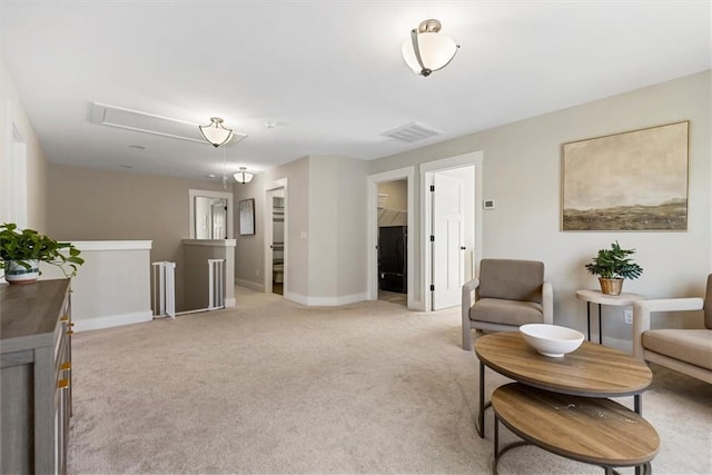 living area featuring attic access, visible vents, baseboards, light colored carpet, and an upstairs landing