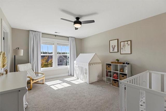 bedroom featuring a crib, carpet, visible vents, and a ceiling fan