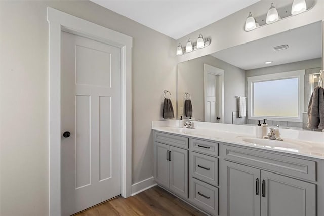 full bathroom featuring double vanity, wood finished floors, a sink, and baseboards