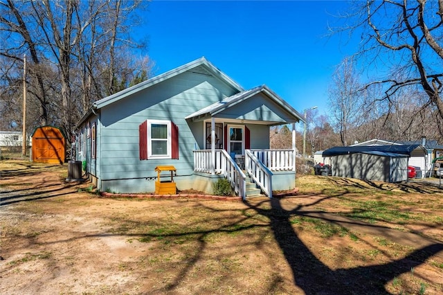 bungalow-style home featuring a porch, cooling unit, crawl space, and a front lawn