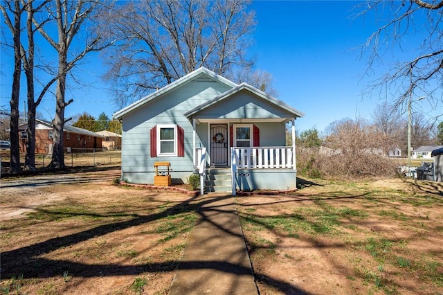 bungalow-style house with covered porch and fence