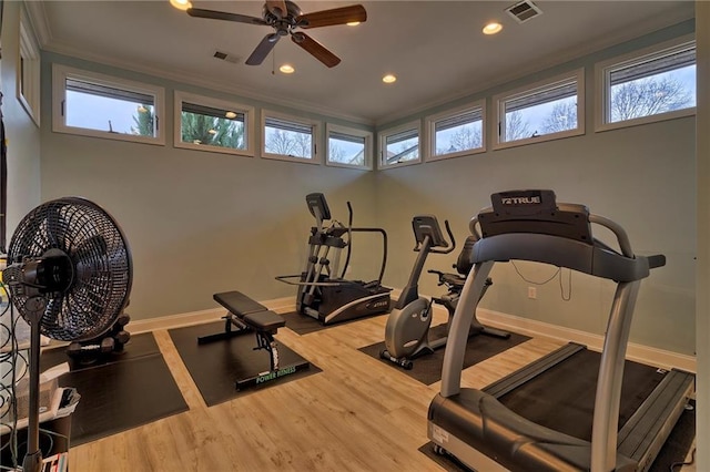 exercise room featuring ornamental molding, wood finished floors, visible vents, and a healthy amount of sunlight