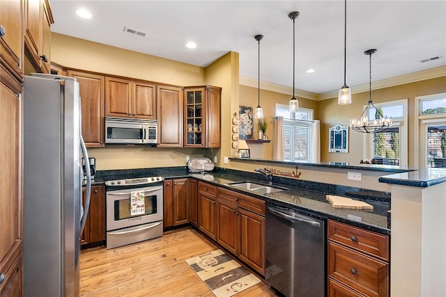 kitchen featuring stainless steel appliances, a peninsula, visible vents, and brown cabinets