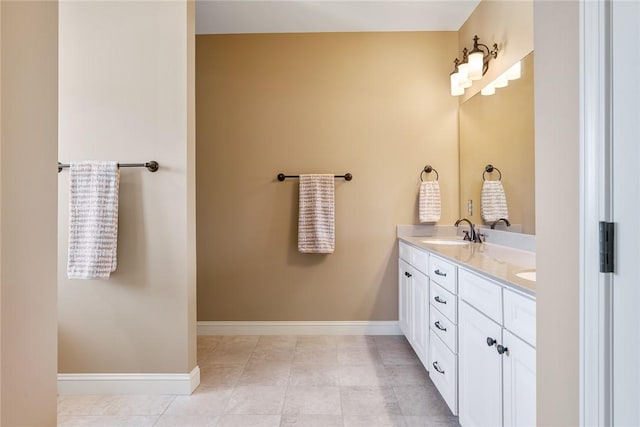 bathroom featuring double vanity, baseboards, a sink, and tile patterned floors