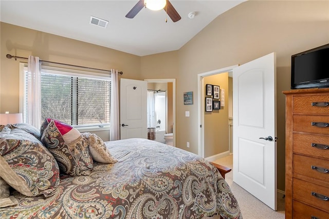 bedroom with visible vents, light colored carpet, ceiling fan, ensuite bathroom, and vaulted ceiling