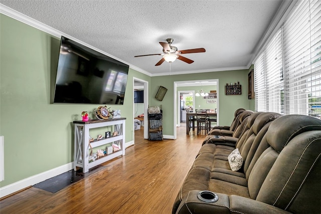 living area featuring crown molding, a textured ceiling, wood finished floors, baseboards, and ceiling fan with notable chandelier