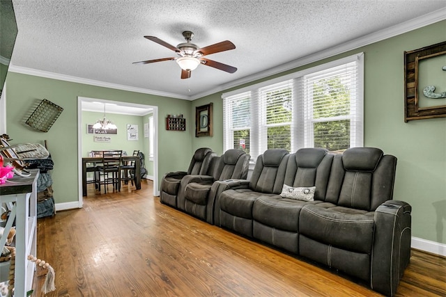 living area with ceiling fan with notable chandelier, ornamental molding, wood finished floors, and baseboards