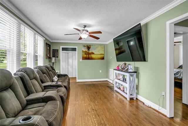 living area with baseboards, a ceiling fan, wood finished floors, crown molding, and a textured ceiling