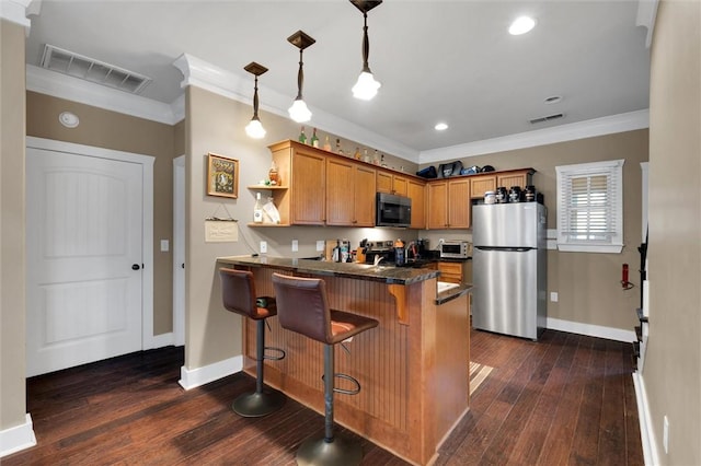 kitchen featuring a peninsula, dark countertops, visible vents, and freestanding refrigerator