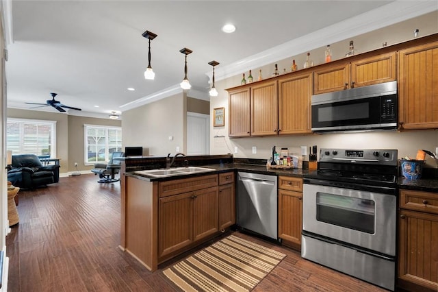 kitchen with stainless steel appliances, dark countertops, open floor plan, a sink, and a peninsula