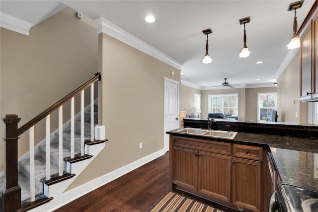 kitchen featuring baseboards, dark wood-type flooring, crown molding, pendant lighting, and a sink