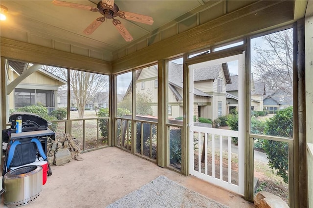 sunroom / solarium with a ceiling fan and a residential view