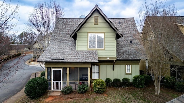 rear view of house with a shingled roof, a sunroom, and board and batten siding