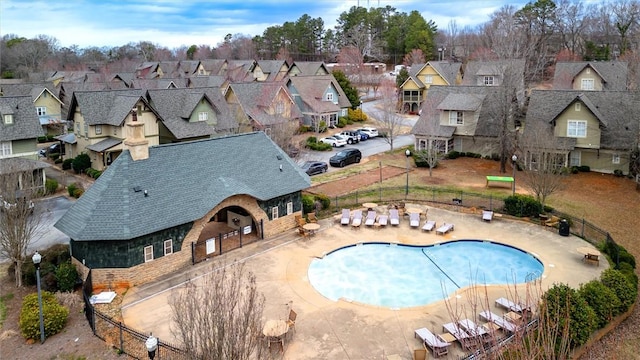 pool with a patio area, fence, and a residential view